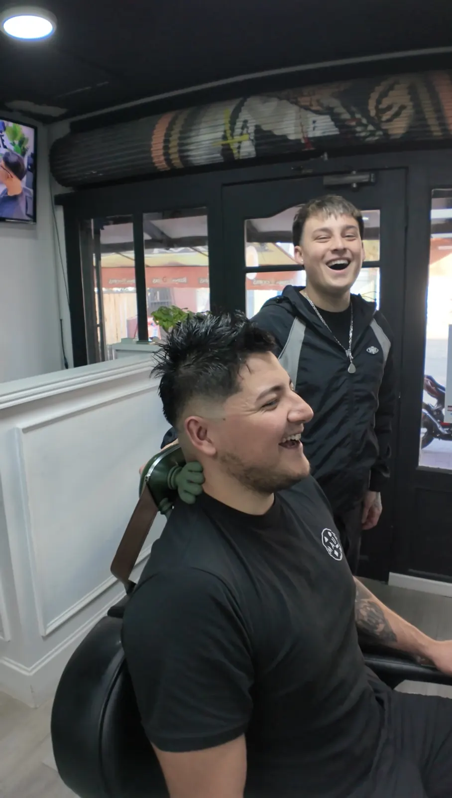 Barbero y cliente riendo durante el corte