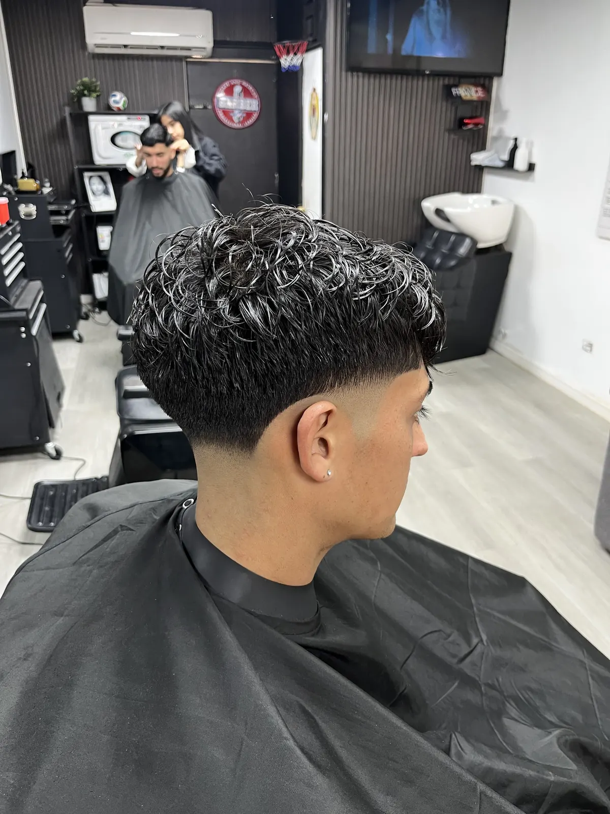 Corte con textura rizada y canas, vista de perfil